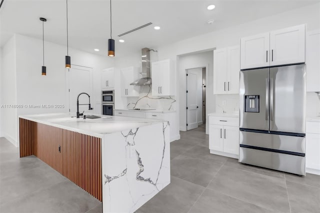 kitchen featuring stainless steel appliances, a sink, white cabinetry, wall chimney range hood, and backsplash