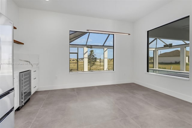 unfurnished living room featuring wine cooler and baseboards