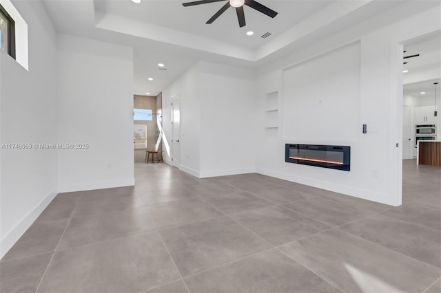 unfurnished living room featuring baseboards, built in features, a glass covered fireplace, heating unit, and recessed lighting