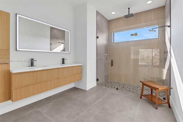 bathroom with tile patterned flooring, a sink, baseboards, double vanity, and a stall shower