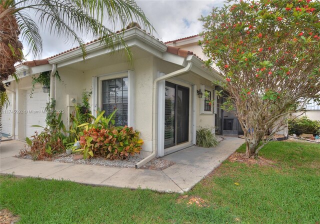 8639 Eagle Run Dr Unit 11, Boca Raton, FL 33434 - view of property exterior featuring stucco siding, an attached garage, a yard, and a tiled roof