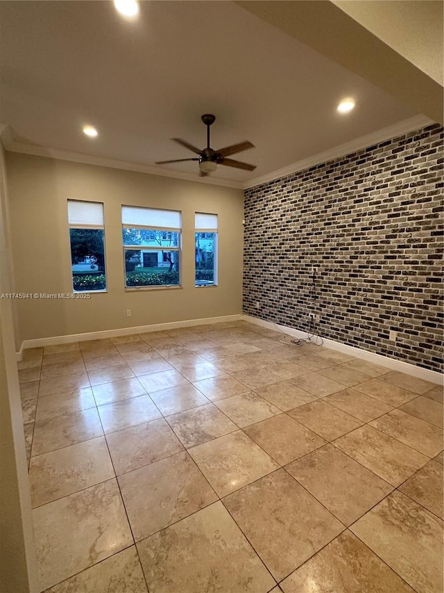 tiled empty room with ceiling fan, ornamental molding, and brick wall