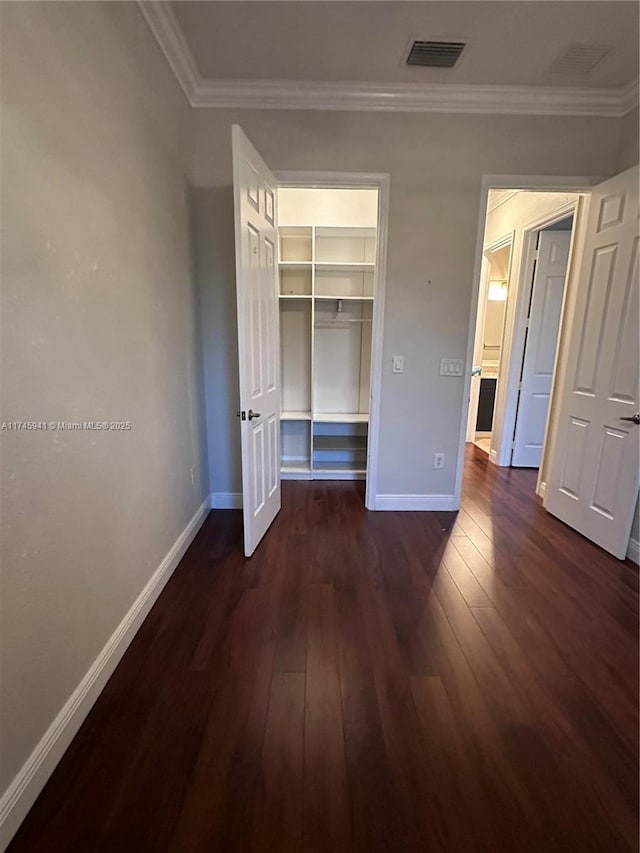 unfurnished bedroom featuring crown molding, a closet, and dark hardwood / wood-style flooring