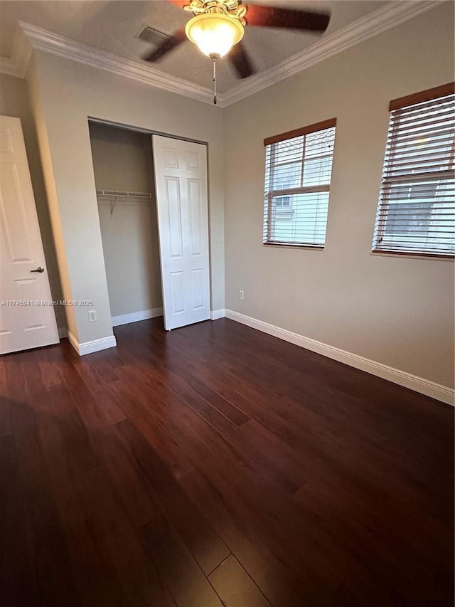 unfurnished bedroom featuring dark hardwood / wood-style flooring, ceiling fan, crown molding, and a closet