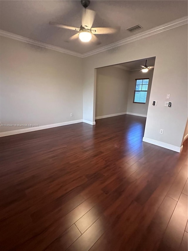 empty room with ceiling fan, dark wood-type flooring, and crown molding