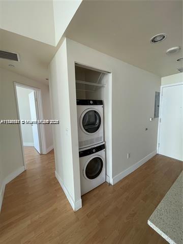 washroom with hardwood / wood-style flooring and stacked washer / dryer