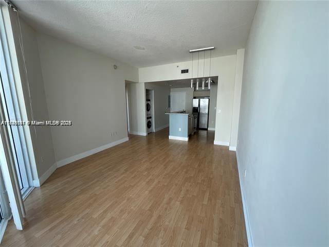 unfurnished living room featuring hardwood / wood-style flooring and a textured ceiling