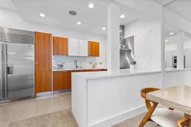 211 Water Way Unit 211, Miami Beach, FL 33141 - kitchen featuring wall chimney range hood, brown cabinetry, a sink, and stainless steel appliances