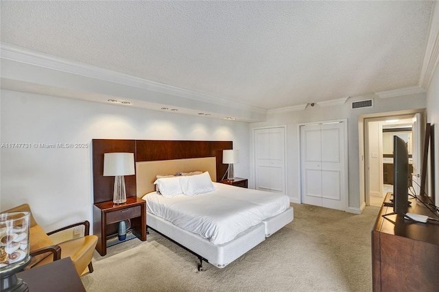 bedroom featuring crown molding, multiple closets, visible vents, and light carpet