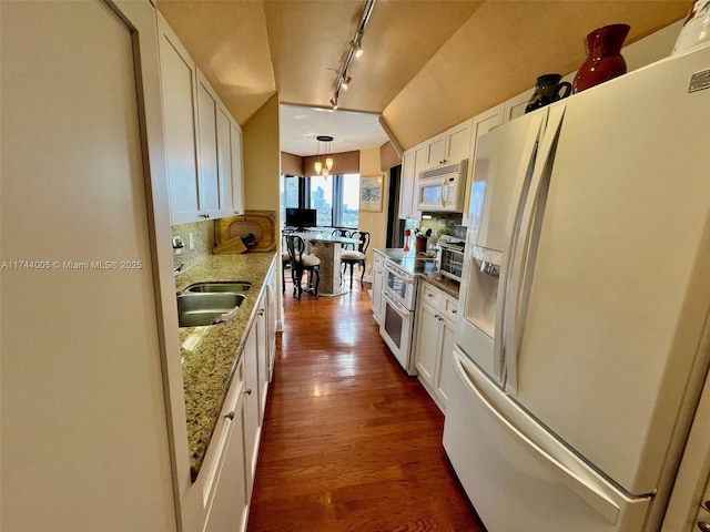 kitchen featuring white appliances, light stone countertops, pendant lighting, sink, and white cabinetry