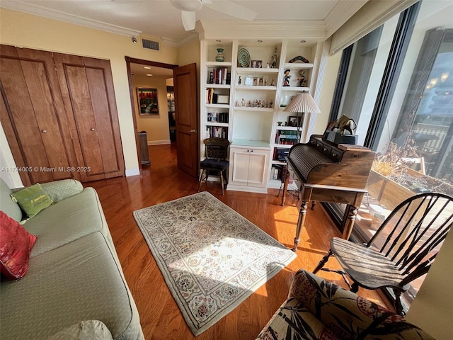 living area featuring hardwood / wood-style floors, ceiling fan, crown molding, and built in shelves