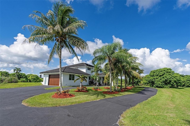 view of front of house featuring a garage, aphalt driveway, and a front yard