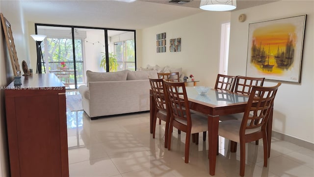 dining space with expansive windows, visible vents, baseboards, and light tile patterned flooring