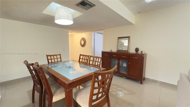 dining room with light tile patterned floors, visible vents, and a textured ceiling