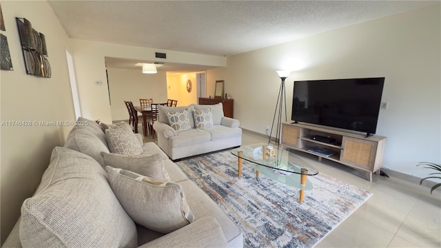 tiled living room featuring visible vents and a textured ceiling
