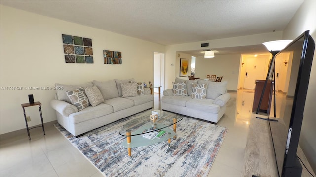 living area featuring light tile patterned floors, visible vents, and a textured ceiling