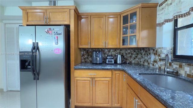 kitchen featuring decorative backsplash, sink, stainless steel fridge with ice dispenser, and dark stone countertops