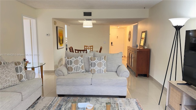 living room with light tile patterned floors, baseboards, and visible vents