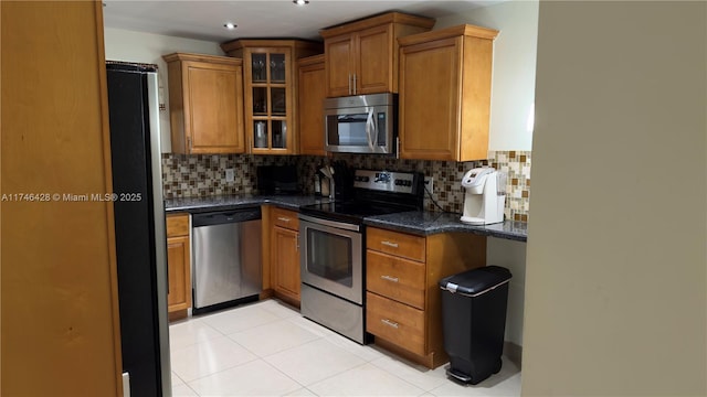 kitchen with decorative backsplash, brown cabinets, stainless steel appliances, and glass insert cabinets