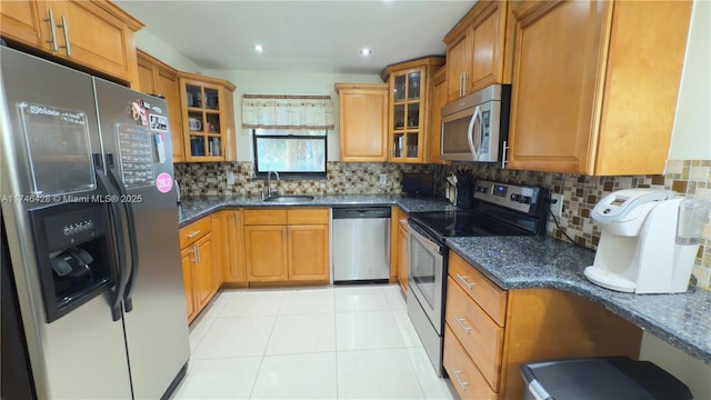 kitchen with dark stone counters, brown cabinetry, appliances with stainless steel finishes, and a sink