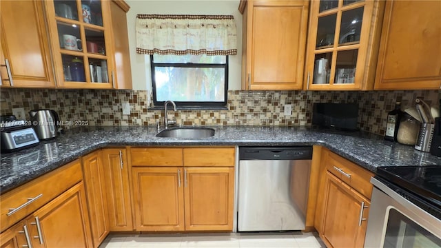 kitchen with decorative backsplash, appliances with stainless steel finishes, dark stone counters, and a sink