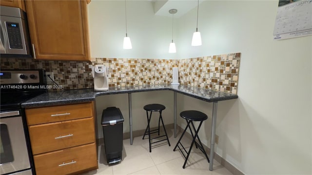 kitchen with tasteful backsplash, light tile patterned floors, appliances with stainless steel finishes, and brown cabinetry