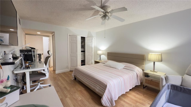 bedroom featuring a closet, light wood-style floors, a ceiling fan, and a textured ceiling