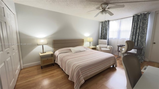 bedroom with light wood-type flooring, baseboards, a textured ceiling, and a ceiling fan