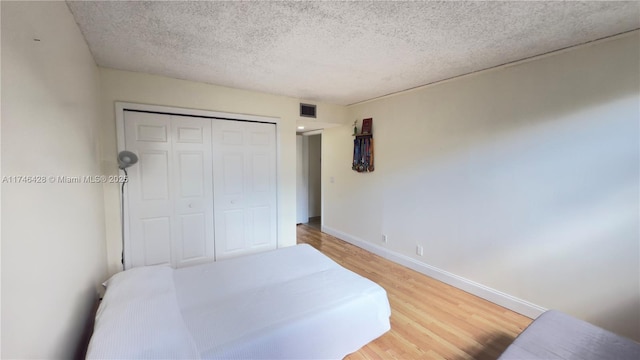 16475 Golf Club Rd Unit 202, Weston, FL 33326 - bedroom with light wood-style flooring, a textured ceiling, baseboards, and a closet