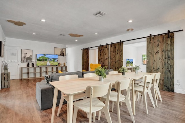 dining room with hardwood / wood-style flooring and a barn door