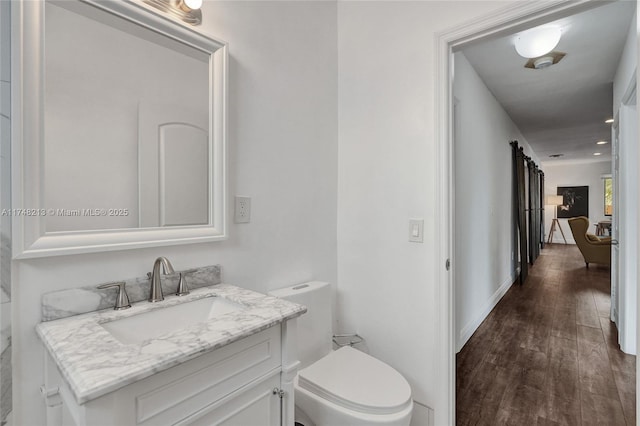 bathroom with toilet, wood-type flooring, and vanity