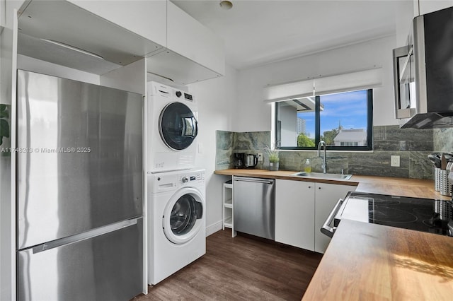 clothes washing area featuring sink, stacked washer / dryer, and dark hardwood / wood-style flooring