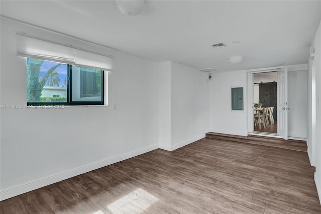 empty room with electric panel and wood-type flooring