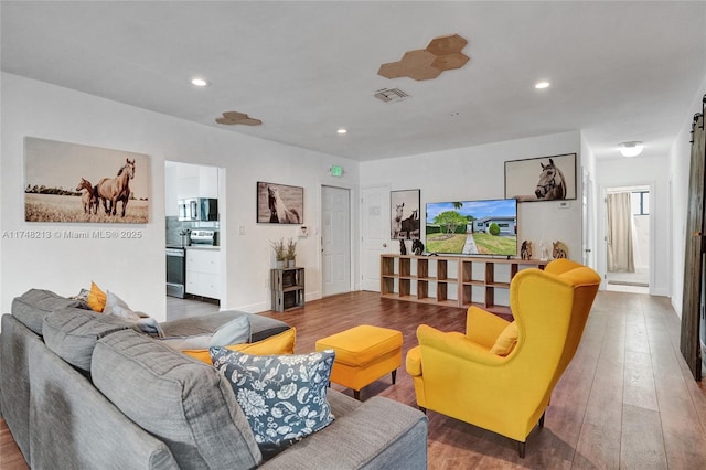 living room with a barn door and wood-type flooring