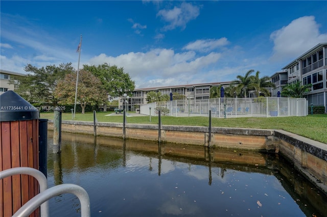 view of dock with a water view and a lawn