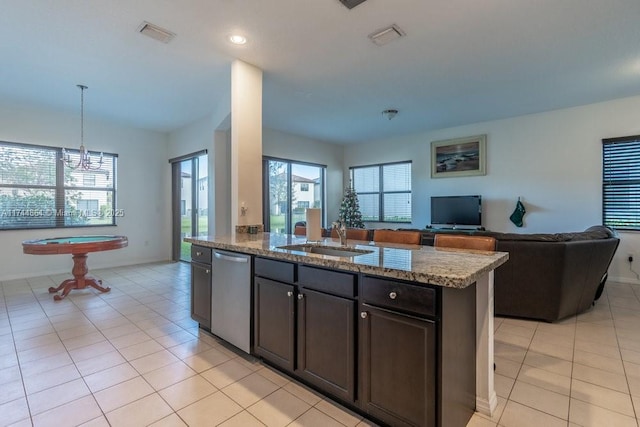 kitchen with dishwasher, an island with sink, light stone counters, pendant lighting, and sink