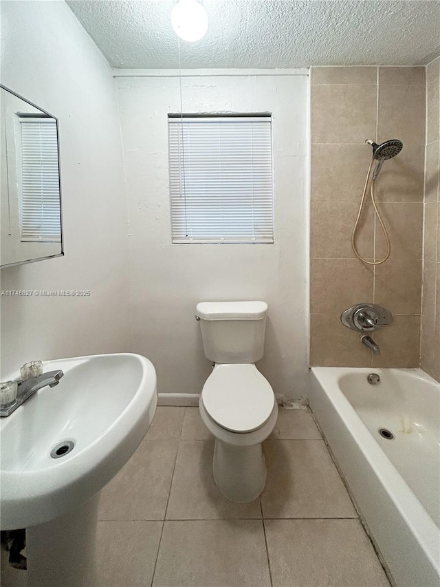 bathroom featuring tile patterned floors, toilet, a textured ceiling, and tiled shower / bath combo