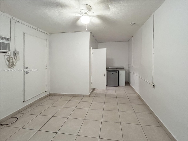 tiled empty room with a textured ceiling and a wall mounted air conditioner