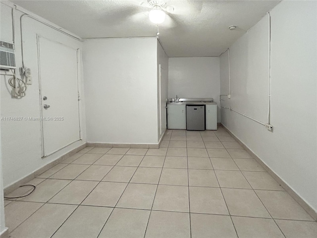 empty room with a textured ceiling, a wall mounted AC, and light tile patterned floors