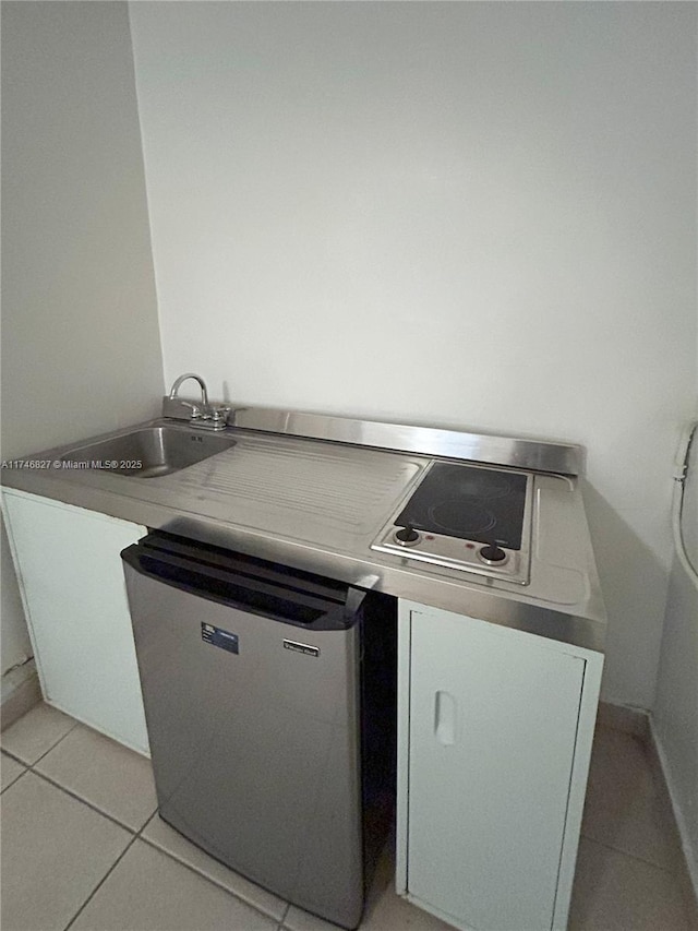 kitchen featuring sink, light tile patterned floors, and dishwashing machine