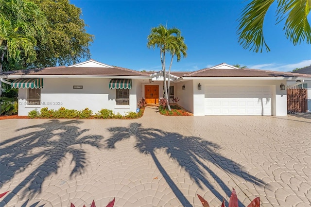 ranch-style house featuring a garage, decorative driveway, and stucco siding