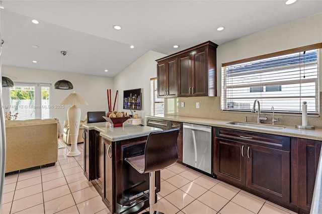 kitchen featuring light tile patterned floors, hanging light fixtures, light countertops, stainless steel dishwasher, and a sink