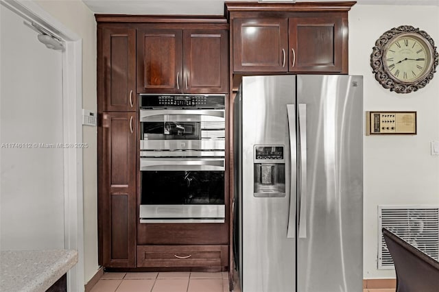 kitchen with light tile patterned floors, dark brown cabinetry, stainless steel appliances, visible vents, and light countertops