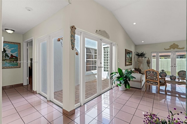 hallway with lofted ceiling, light tile patterned floors, and french doors