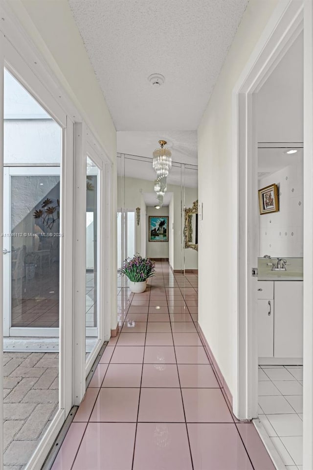 corridor with a sink, a chandelier, a textured ceiling, and tile patterned floors