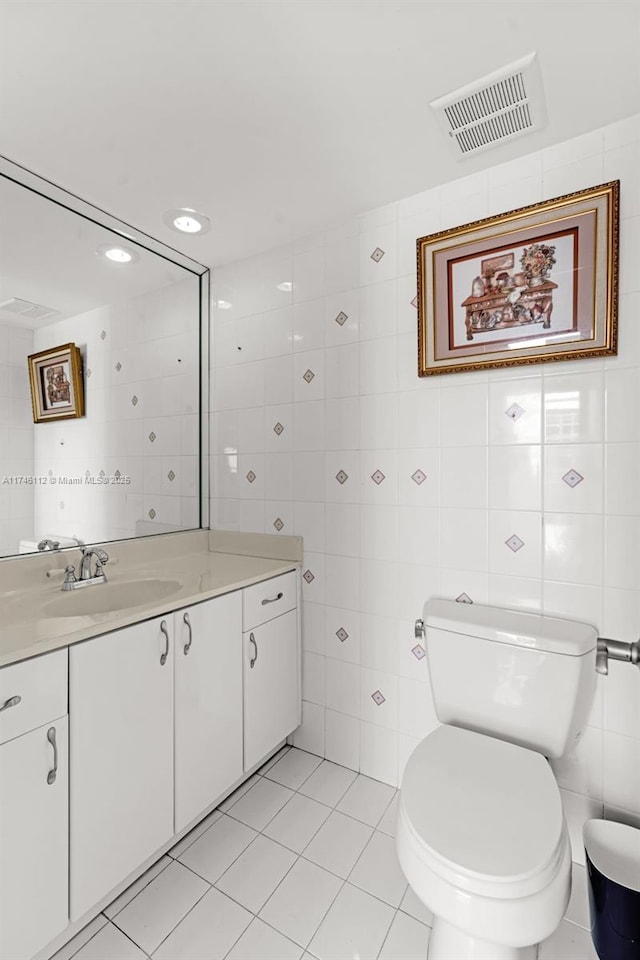 bathroom with vanity, visible vents, and tile walls