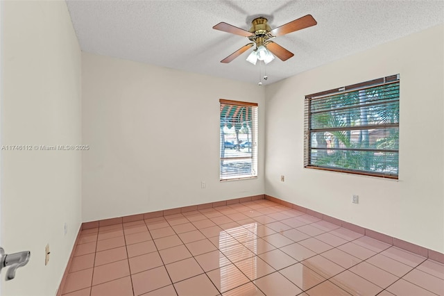 empty room featuring light tile patterned floors, a textured ceiling, and a ceiling fan