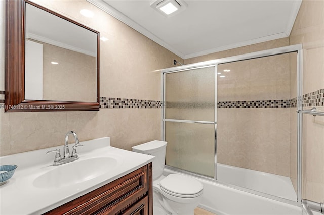 full bath featuring enclosed tub / shower combo, toilet, vanity, tile walls, and ornamental molding