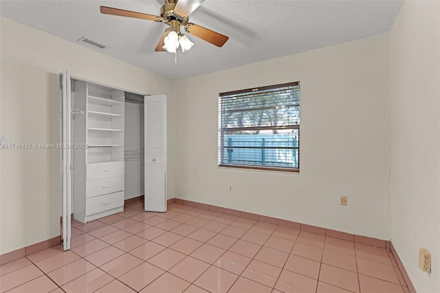 unfurnished bedroom with a textured ceiling, a closet, light tile patterned flooring, and visible vents