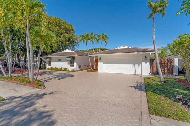 ranch-style house with an attached garage, fence, decorative driveway, and stucco siding